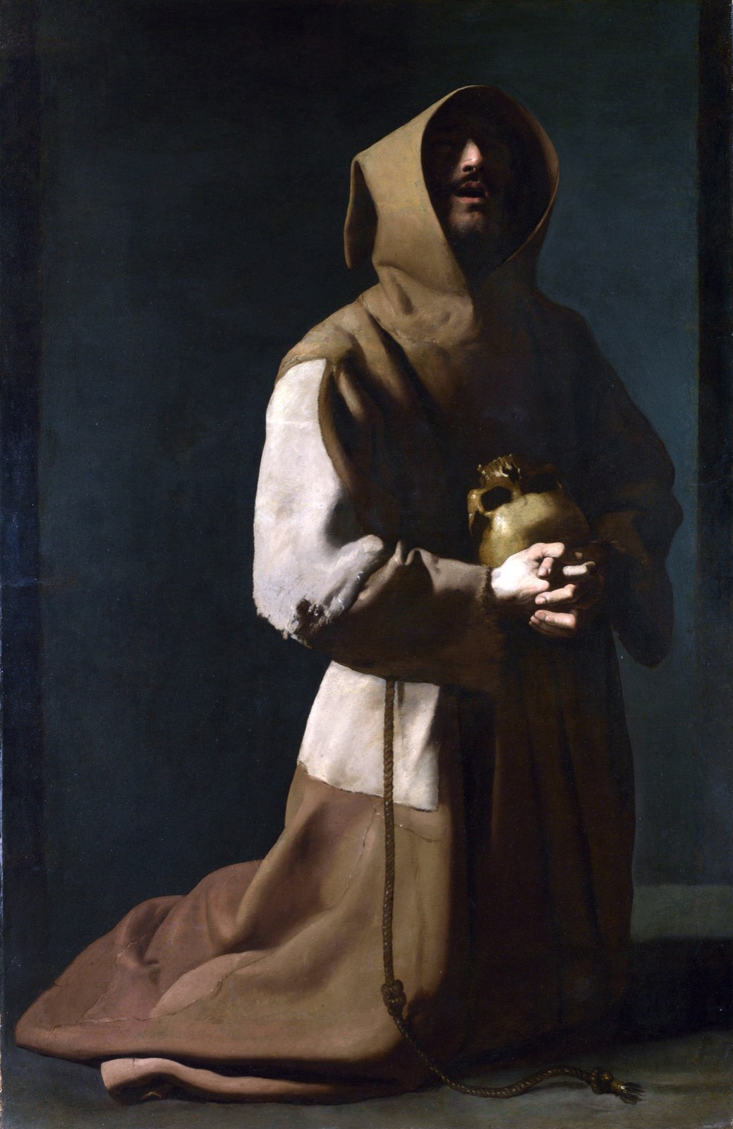 Saint Francis kneeling in a hooded habit, a skull clasped in his hands, his shadowed face lifted upward
